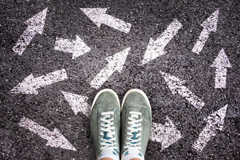 Sneaker Shoes And Arrows Pointing In Different Directions On Asphalt Ground, Choice Concept